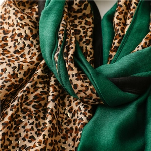 Macro detail of emerald green scarf with gold leopard print pattern and soft fabric texture