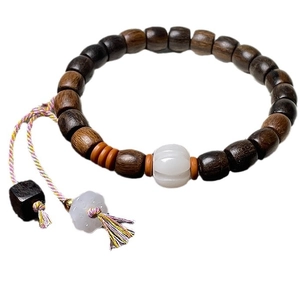 Sandalwood beaded bracelet with white pumpkin charm and colorful tassel on white background