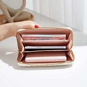 White zip-around wallet with gold patterns showing internal phone and card storage