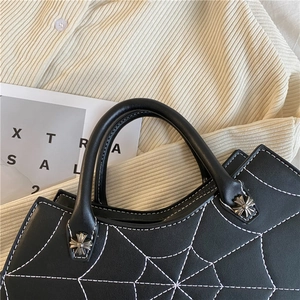 Schwarze PU Leder Handtasche Detail, weiße Spinnennetz Nähte und dekorative Metallkreuz Akzente.