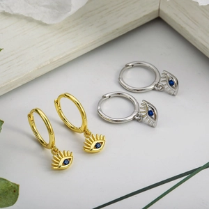 Detail of gold and silver evil eye hoop earrings with blue zircon in close-up view