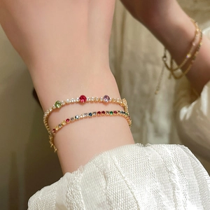 Close-up of elegant gold-plated tennis bracelets with colorful zircons on a woman's wrist