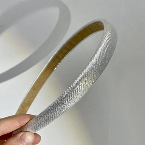 Macro detail of a thin silver headband with metallic shimmer and beige inner lining