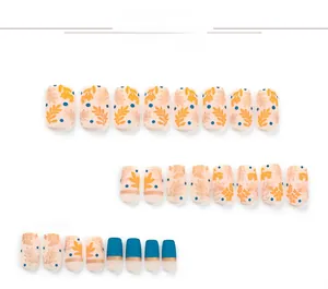 Detail view of nail patches with orange leaf patterns, blue dots, and gold metal stripes
