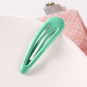 Close-up of a mint green water drop hair clip on a white ceramic plate edge