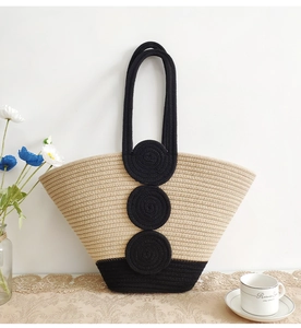 Detail of woven straw tote bag featuring black spiral patterns on lace tablecloth