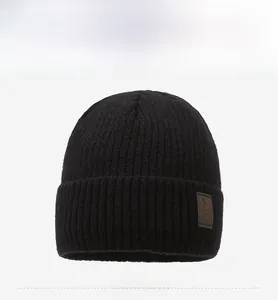 Close-up of black ribbed knit beanie featuring a premium brown leather logo patch