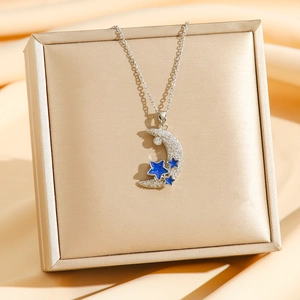 Star and moon necklace with blue accents and white zircons on champagne silk display