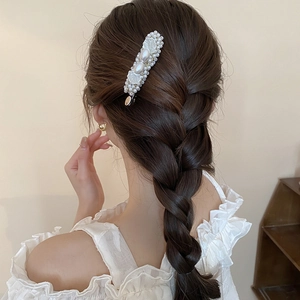Elegant pearl hair clip with seashell accents worn on braided hair for women