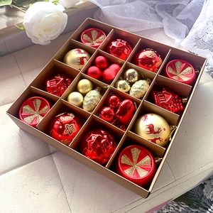 Close-up of a gift box filled with diverse red and gold Christmas ornaments and baubles