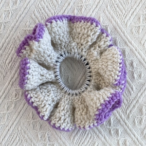 Close-up of crochet ruffle scrunchie with cream cotton base and purple wavy stitched edges
