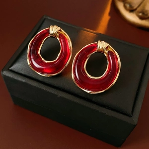 Close-up of vintage resin earrings with red oval pendants and golden metal frames