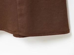 Detalle de costuras impecables y textura de tela marrón oscuro en vestido midi