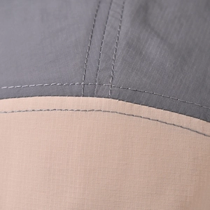 Macro detail of tear-resistant fabric with khaki and grey blocks and dual stitching