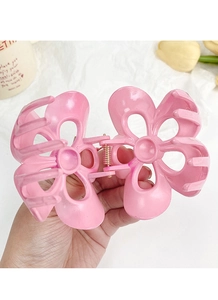 Gros plan sur la pince à cheveux fleur de frangipanier rose avec ressort doré brillant