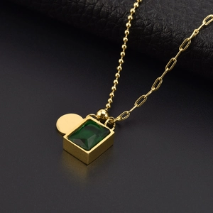 Detail of gold necklace with green rectangular gem on premium black leather