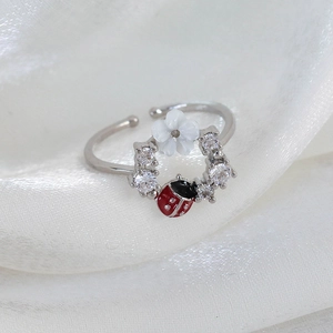 Macro shot of silver adjustable ring featuring ladybug and floral zircon accents