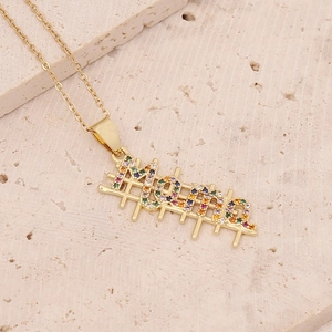 Macro detail of 18K gold Mama pendant with colorful zircon stones on textured stone