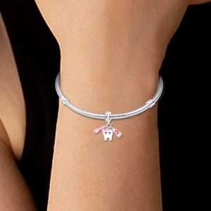 Detail of 925 sterling silver snake chain bracelet with tooth, toothbrush, and toothpaste charms