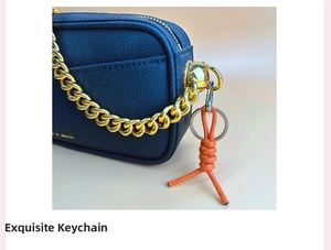Close-up of blue lychee leather bag with orange woven knot and gold chain detail