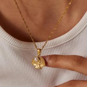 Detailed shot of golden shell pendant with white pearl and female art relief motif