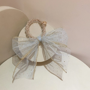 Dettaglio elastico per capelli con fiocco in rete azzurra e paillettes dorate
