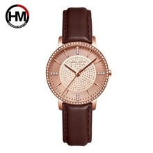Detailed close-up of rose gold watch dial with sparkling crystals and brown leather strap
