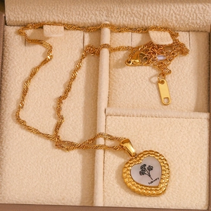 Gros plan d'un pendentif cœur plaqué or 18 carats avec gravure de fleur de naissance de février