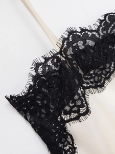 Close-up of black eyelash lace trim on ivory satin camisole with thin strap detail