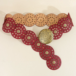 Close-up of vintage deep red circular leather belt with antique bronze metal buckle