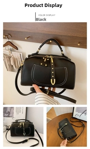 Détail du sac bandoulière noir avec coutures blanches et garnitures dorées en forme de U