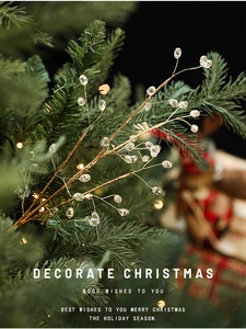 Detail of a golden Christmas branch with clear beads on a festive tree branch