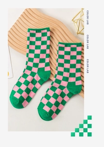 Close-up of pink and green checkerboard knit socks on a designer wooden display tray