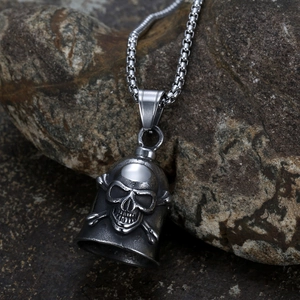 Retro stainless steel skull guardian bell pendant on box chain over a rugged rock surface