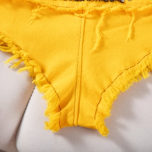 Vista dettagliata dei pantaloncini di jeans gialli con bordi sfilacciati e dettagli a nappe