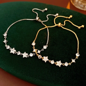 Detailed view of gold and silver zircon star bracelets on dark green velvet background