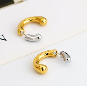 Close-up of dual-tone gold and silver C-shaped tubular earrings with polished finish