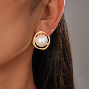 Close-up of a gold irregular ring earring with a large white pearl on a model ear