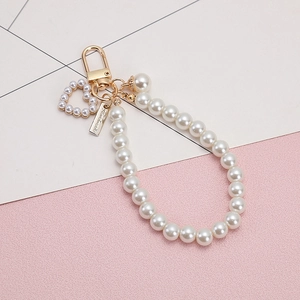 Creative heart pearl keychain with golden clasp and handmade tag on pink background