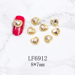 Detalle de joya de uña de corazón champán de 8x7mm con marco de metal dorado en mármol