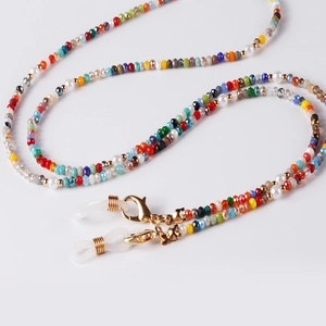 Detail of colorful faceted beads and faux pearls with gold lobster claws on a glasses chain