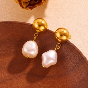 Macro shot of 18k gold-plated ball studs with baroque pearl tassels on wood tray