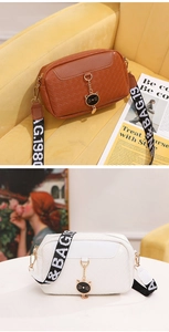 Close-up of woven texture crossbody shell bag with cat charm and wide strap