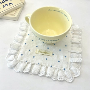 Macro view of white cotton coaster with blue heart pattern and exquisite lace edges