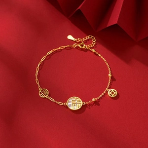 Detailed shot of golden lucky charm bracelet with shell inlay on a vibrant red background