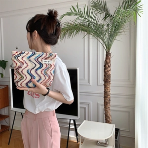 Detail of multi-color wavy knit makeup bag with rainbow embroidery and Korean woven label