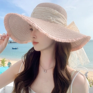 Detail of light pink straw sun hat with large lace bow, pearls and delicate lace trim