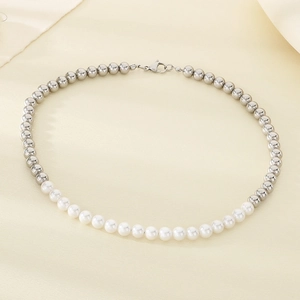 Détail d'un collier de perles argentées et perles blanches avec fermoir mousqueton sur tissu