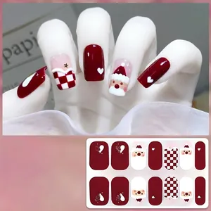Detail of Christmas gel nail wraps with Santa and red checkerboard patterns