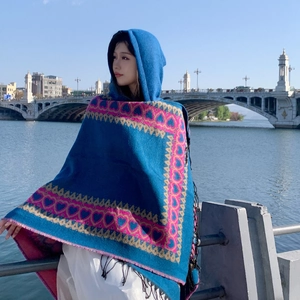 Détail d'un poncho ethnique à capuche avec motifs de cœur et franges noires en extérieur